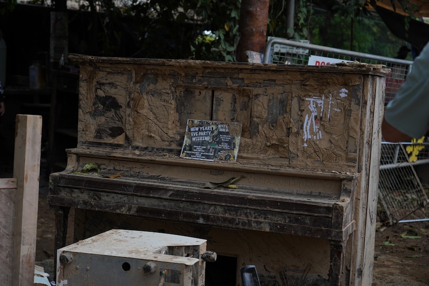 The piano was caked with brown mud and the sheet music was still on the lid.