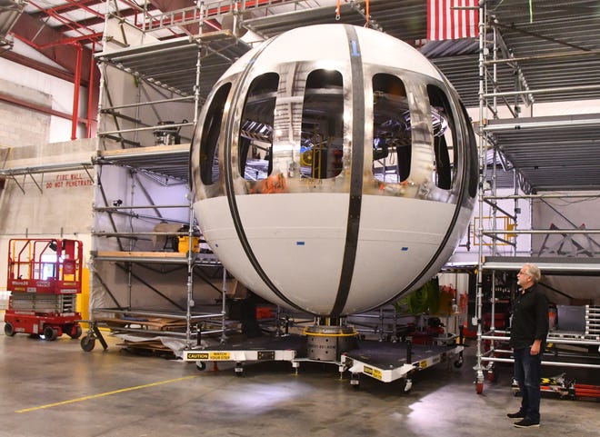 Space Perspective co-CEO Taber MacCallum stands next to the 14-foot-diameter Neptune spacecraft under construction in a hangar at the Space Coast Regional Airport in Titusville.