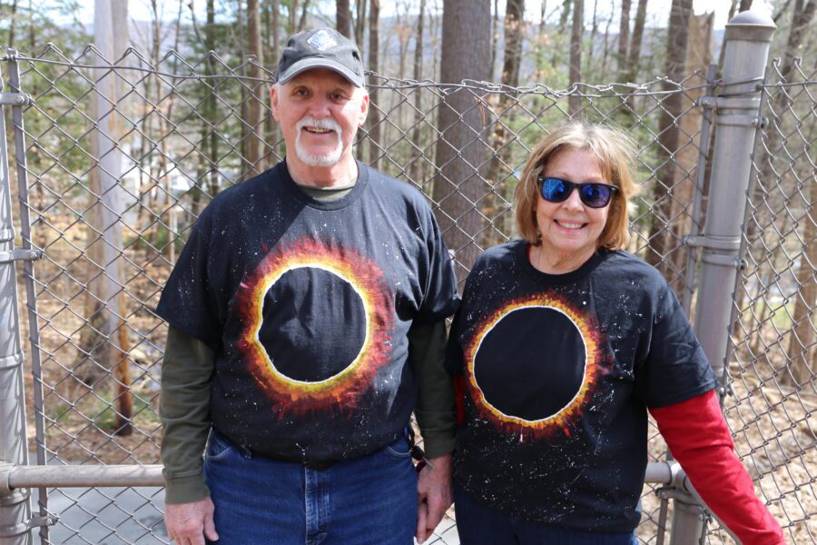 Lake George residents Peter and Joyce Hawthorne stood on the North Road Bridge leading to Prospect Mountain in Lake George, waving to cars passing below. They wore homemade T-shirts depicting the solar eclipse.