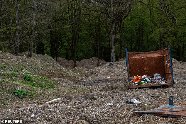 A metal container lies amid a mountain of illegally dumped waste