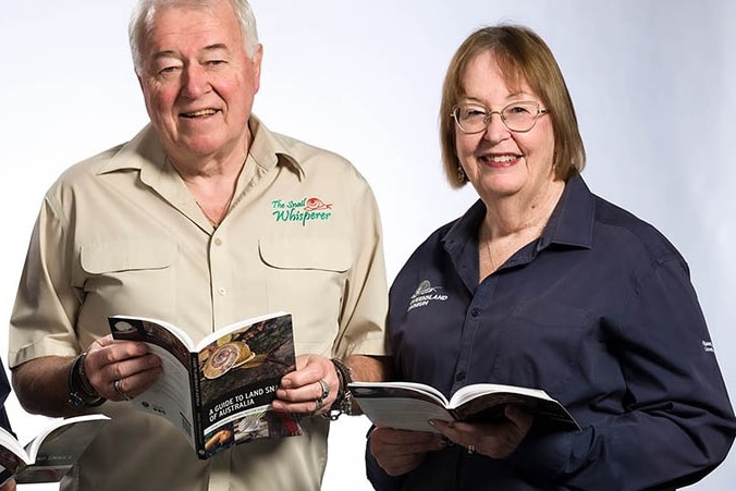 A man and a woman each holding a book and smiling