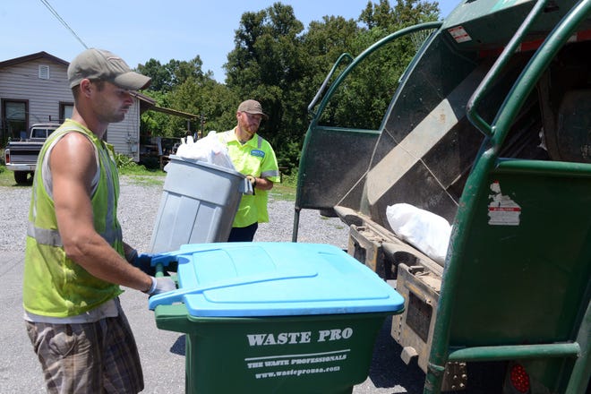 Waste Pro workers load trash into back-loading bins. Sometimes the seals on these trucks can become damaged, causing waste