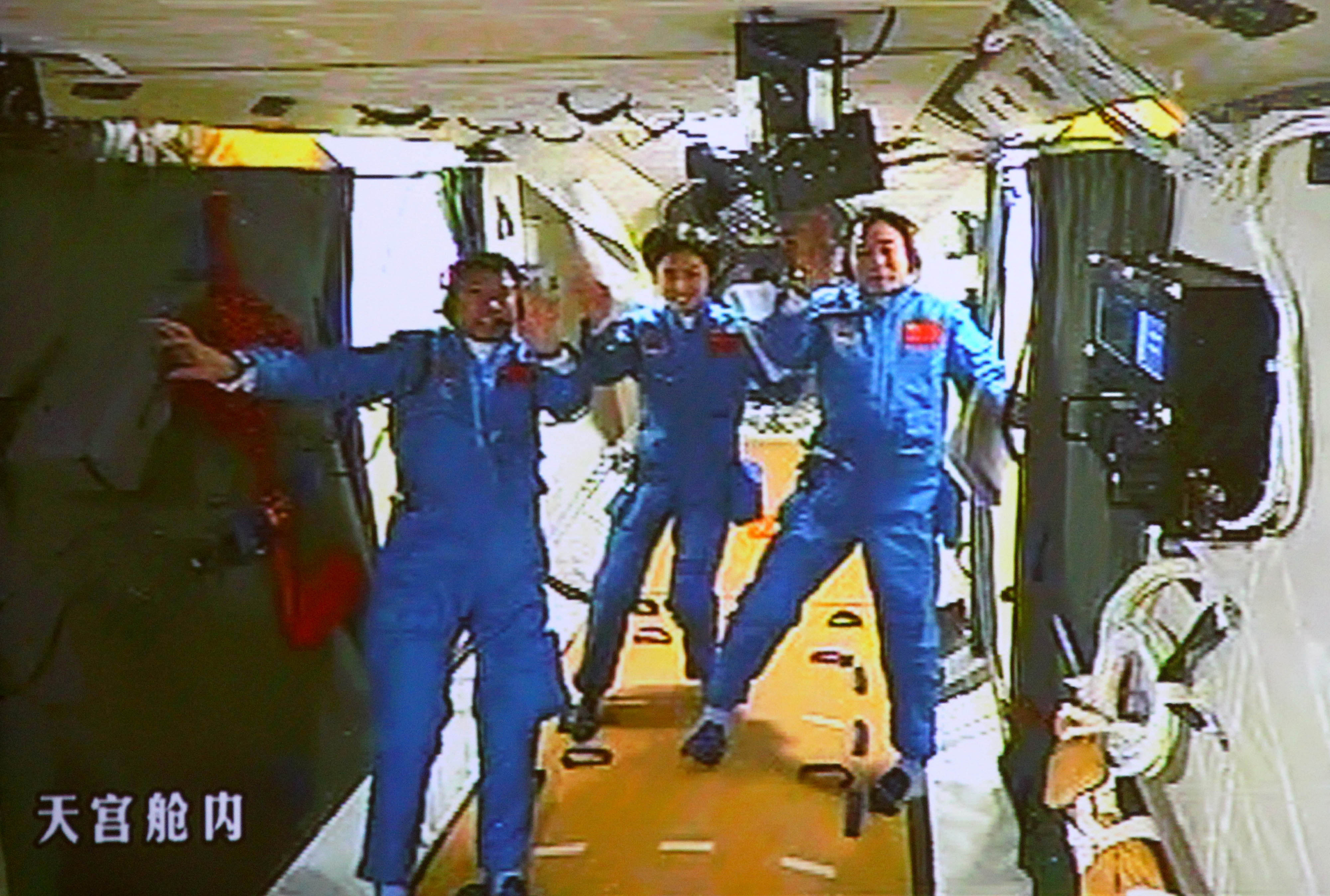 Chinese astronauts Liu Wang, Liu Yang and Jing Haipeng wave on board the Tiangong-1 space station