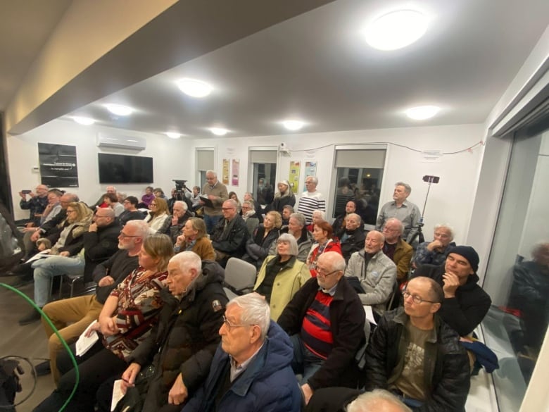 A room packed with people attending a town hall