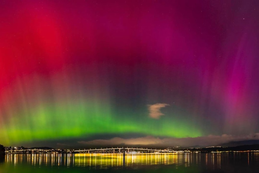 Hobart-Tasman Bridge at night, the sky is illuminated by the Australian Aurora, showing green, red and pink colors