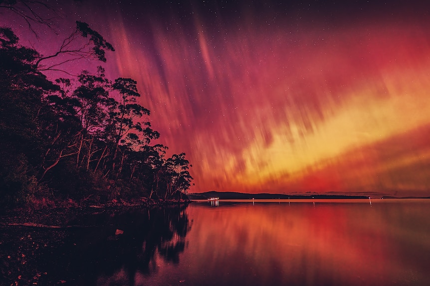 Australia's auroras illuminate pink, orange and yellow colors over rivers